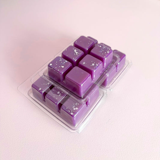 Purple wax melts in a clear plastic mold on a light pink background